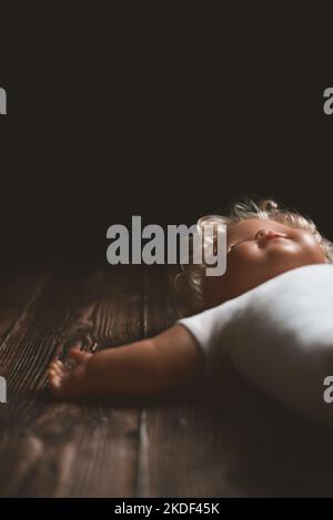 Lost old blonde toy doll with closed eyes lying on the floor Stock Photo