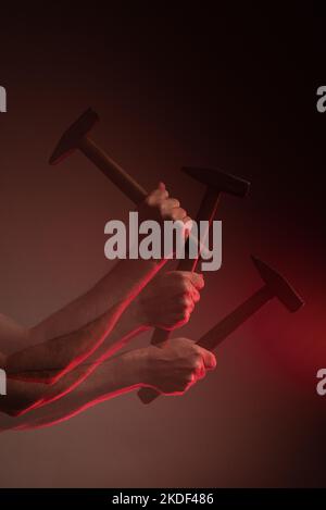 Triple exposure of a male hand hitting with a hammer Stock Photo