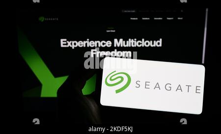 Person holding smartphone with logo of US data storage company Seagate Technology LLC on screen in front of website. Focus on phone display. Stock Photo