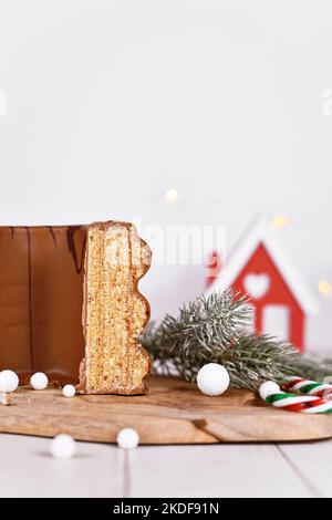 Cut open traditional German layered winter cake called 'Baumkuchen' glazed with chocolate, surrounded by seasonal decoration Stock Photo