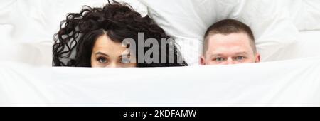 Man and woman covering with white blanket, awake couple in bad Stock Photo