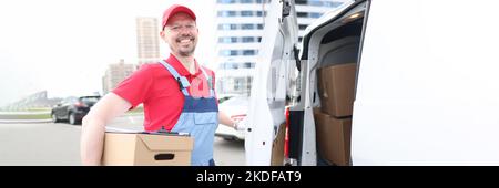 Smiling courier with parcels near delivery van Stock Photo