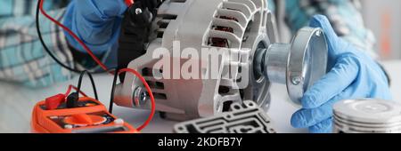 Handyman in gloves repairing automobile part and measuring voltage Stock Photo