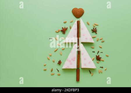 white cake christmas tree shaped with Gingerbread, anise stars, cinnamon pie flat lay on green table Stock Photo