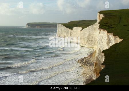 Dramatic shoreline scene on rugged white cliff coastline in south England. Seven Sisters Cliffs view looking towards Seaford Head as tide comes in Stock Photo