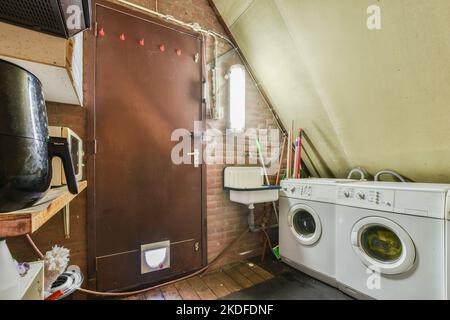 spacious mansard styled laundy room and storage with washing machine Stock Photo