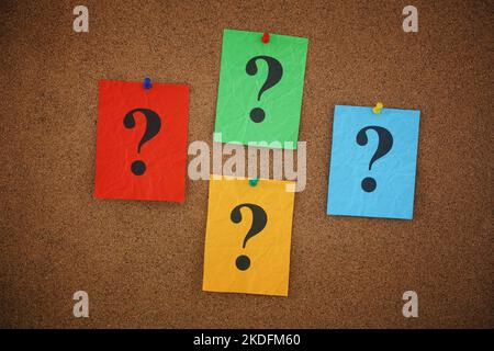 Colorful crumpled paper notes with question marks on them pinned to a cork board. Closeup. Stock Photo