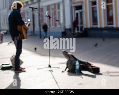 Defocused image of street musician with acoustic guitar on pedestrian street on sunny day. Ukraine, Zhytomyr, November 04, 2022 Stock Photo