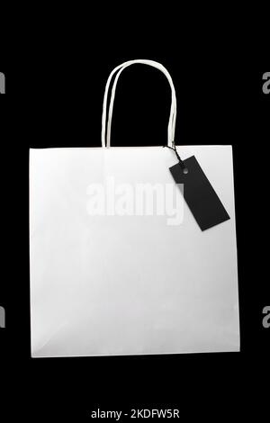 One empty white paper shopping package with blank tag on black. Black friday, online shopping, Boxing day, Father's day, Valentine's day, Christmas sa Stock Photo
