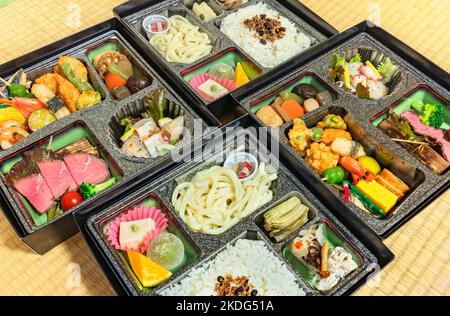 Deluxe Japanese Makunouchi bento boxes with rice,udon noodles, assortment of tsukemono preserved and nimono simmered vegetables, roast beef slices, sa Stock Photo