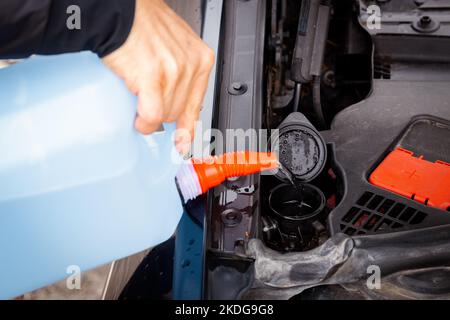 Adding winter windshield washer fluid, Preparing the car for winter driving, Changing weather conditions on the road Stock Photo