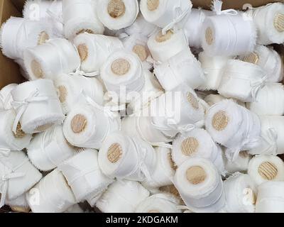 White silk ribbons with wooden spools a lot. Top view, Closeup. Texture background, market, counter. Stock Photo