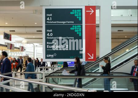 Visitors on escalator going past direction signs at CHPI 2022 in Messe Frankfurt, Germany Stock Photo