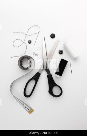 black and white thread coils, scissors, pin and tape measure on white background, sewing, handmade concept, design for seamstress and tailor Stock Photo
