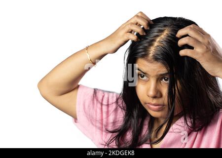 An Indian woman worried due to hair loss problem holds scalp on white background Stock Photo