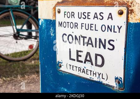 Old fashioned petrol, gas or gasoline fuel pump with lead and Tetraethyl warning sign and a bicycle in the background Stock Photo