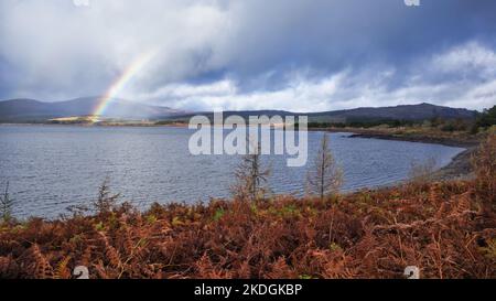 View with rainbow over Clatteringshaws loch in Galloway forest park in Ayrshire Scotland Stock Photo