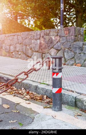 Rusty old chain connected to a pole of a private street car parking close-up Stock Photo