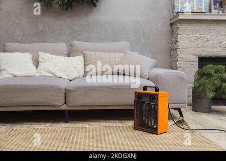 Electric fan heater on floor in living room witgh couch and chimney Stock Photo