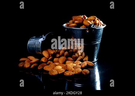 Peeled almond in jar glass bucket on a black isolated background. Row of bowls with almond nuts, front view. Peeled almond pattern Stock Photo