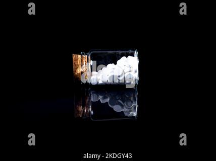 white orange pills in wineglass glass . in jar. in bucket Isolated on black set of capsule and pills inside wineglass closeup, selective focus, side v Stock Photo
