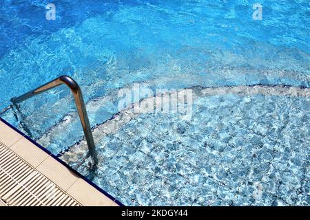 Steps for descending into the swimming pool with a metal handrail. Safety for water sports Stock Photo