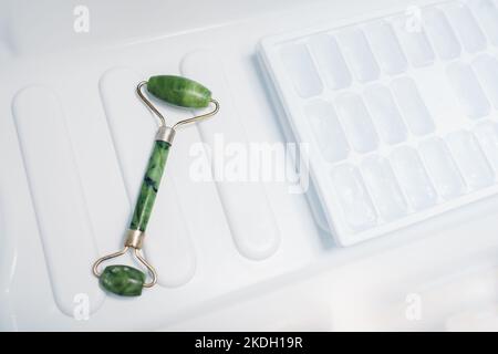 Storage of beauty tool in fridge. Jade roller for facial massage put in freezer with ice. Skin care product cooling Stock Photo