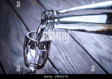 Pouring vodka from bottle into shot glass, selective focus Stock Photo