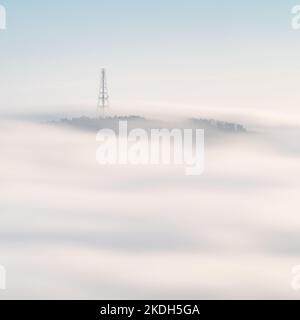 The radio mast atop Norwood Edge is visible above a soft white blanket of mist during an autumn temperature inversion filling the Washburn Valley. Stock Photo