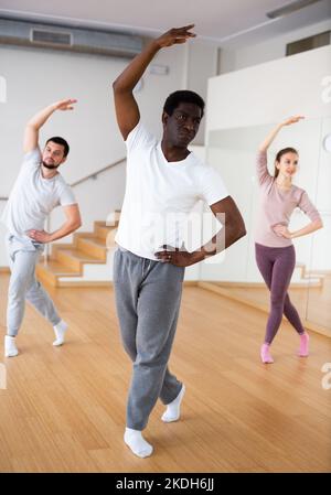 African-american man practicing classical dance moves with group Stock Photo