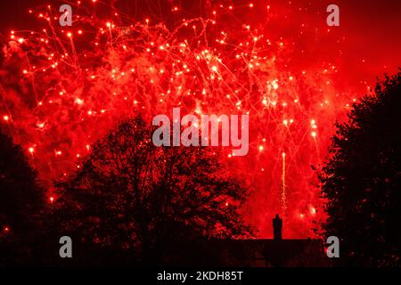 Fireworks exploding in the sky silhouette of buyer cottage and trees red and yellow Stock Photo