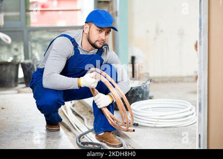 Man electrical installer laying cables through trench Stock Photo