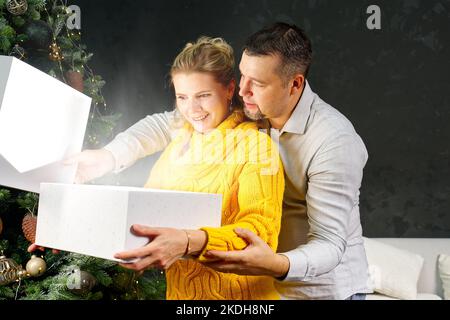 Man giving a Christmas present to his girlfriend. Opening gift box at christmas time. Christmas wonder concept Stock Photo