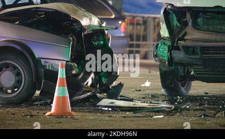 Damaged in heavy car accident vehicles after collision on city street crash site at night. Road safety and insurance concept Stock Photo