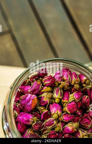 A glass container filled with dried rose buds to make tea Stock Photo