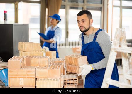 Repairman carrying bricks in construction site Stock Photo