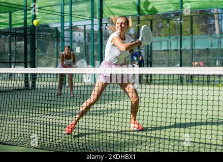 Woman in shorts playing padel tennis on court Stock Photo