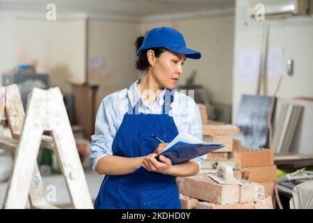 Woman making notes on indoor construction site Stock Photo