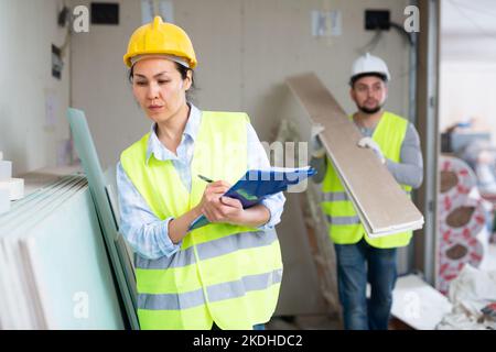 Female building inspector taking inventory of materials at construction site Stock Photo