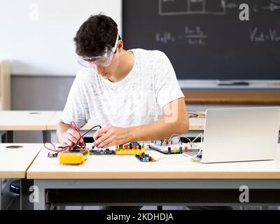 Young male student experimenting with electronic devices in the laboratory Stock Photo