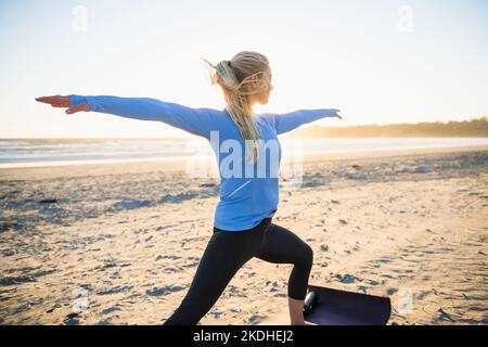 Young woman doing yoga at the beach during golden hour Stock Photo
