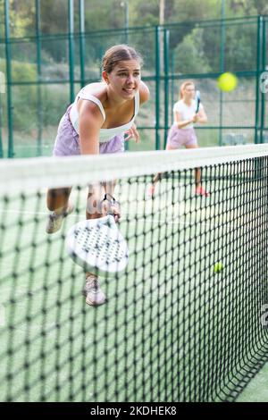 Girl playing padel tennis match during training on court Stock Photo