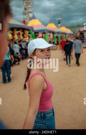 Teen girl talking to someone out of focus at a carnival Stock Photo