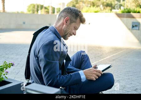 Smiling businessman with skateboard using tablet on platform Stock Photo