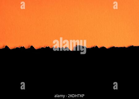 Torn half sheet black paper horizontal on orange paper at the bottom. As template for message or advertisement. Stock Photo