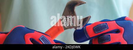 Worker in gloves holds wrench for plumbing repairs Stock Photo