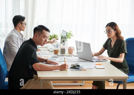 Group of young engineers working at big table in architecture bureau Stock Photo