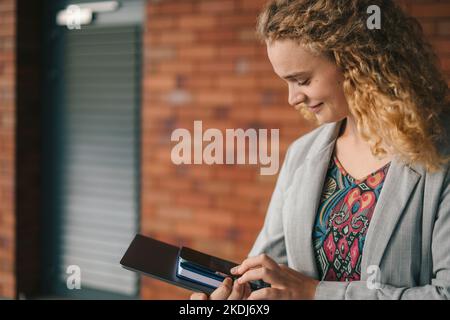 Young caucasian curly-haired woman smiling happy using smartphone at the city. Modern lifestyle. Distance education. Internet communication, wireless Stock Photo