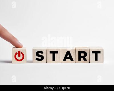 Finger presses the start button on wooden cubes. Start up business, starting a new career or life concept. Stock Photo