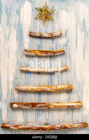 An original alternative Christmas tree made from branches and decorated with a tiny garland. Stock Photo
